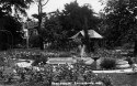 Black and white photo of a garden with a fountain, flowers, and trees, labelled "Rose Garden, Ravenscourt Park.